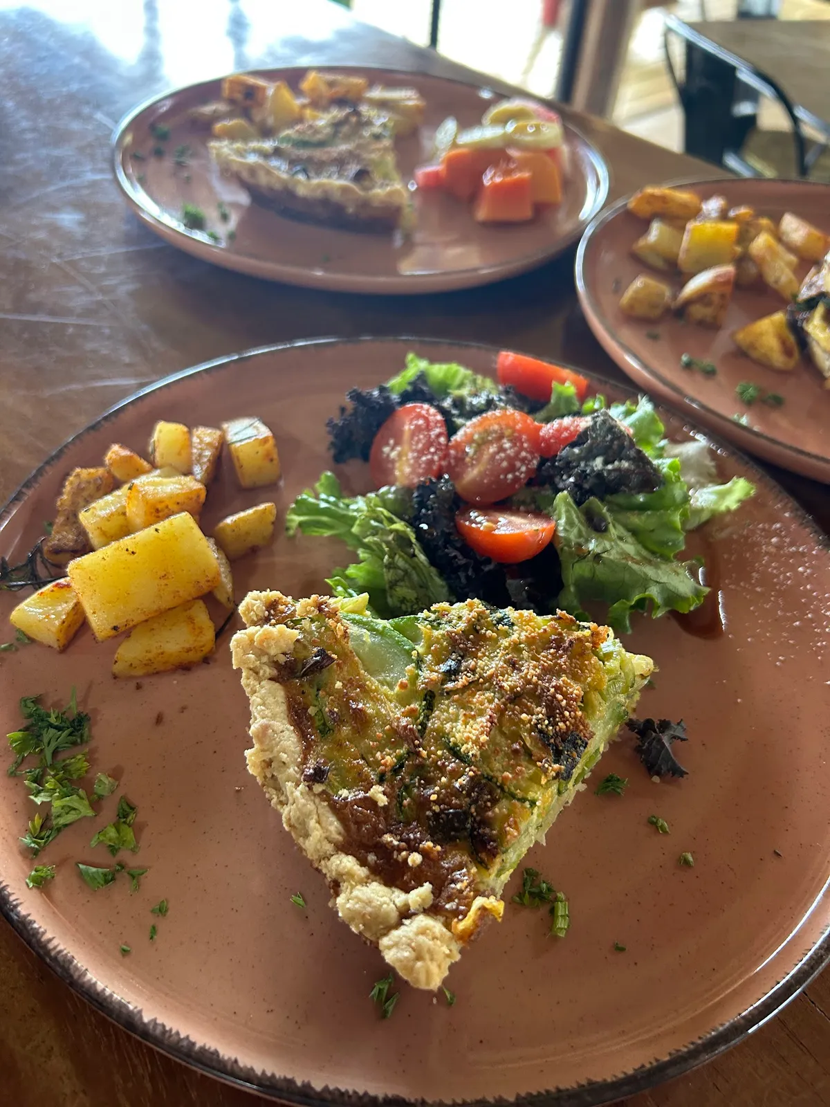Zucchini quiche with salad and rosemary potatoes on terracotta plates